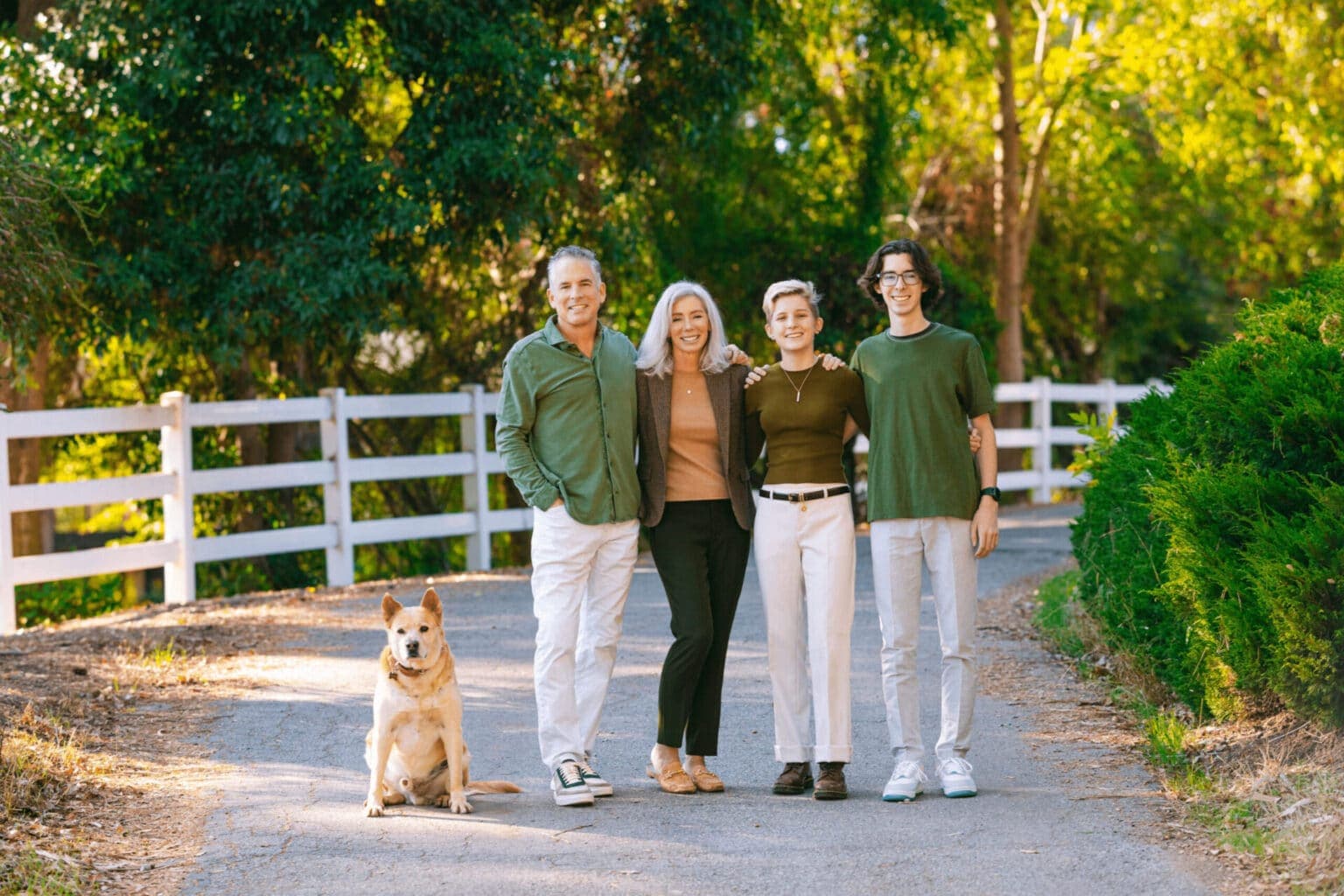 Family walking outdoors with a dog, captured in natural, warm-toned environment.