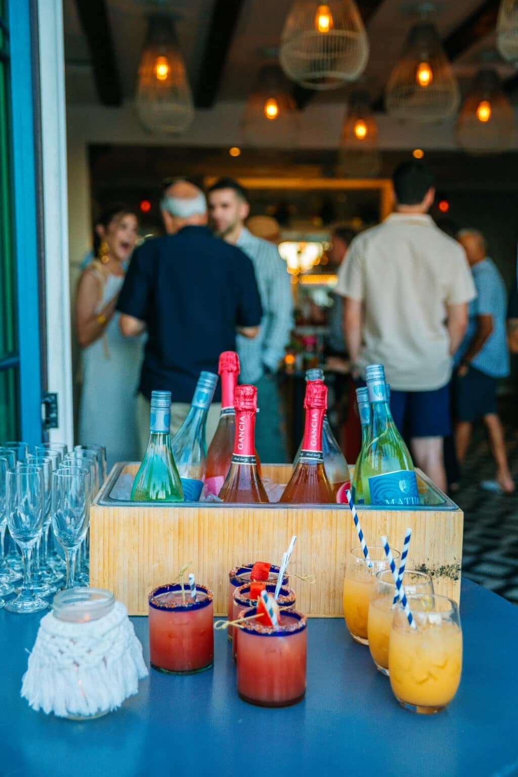 Outdoor event bar with cocktails and guests mingling.