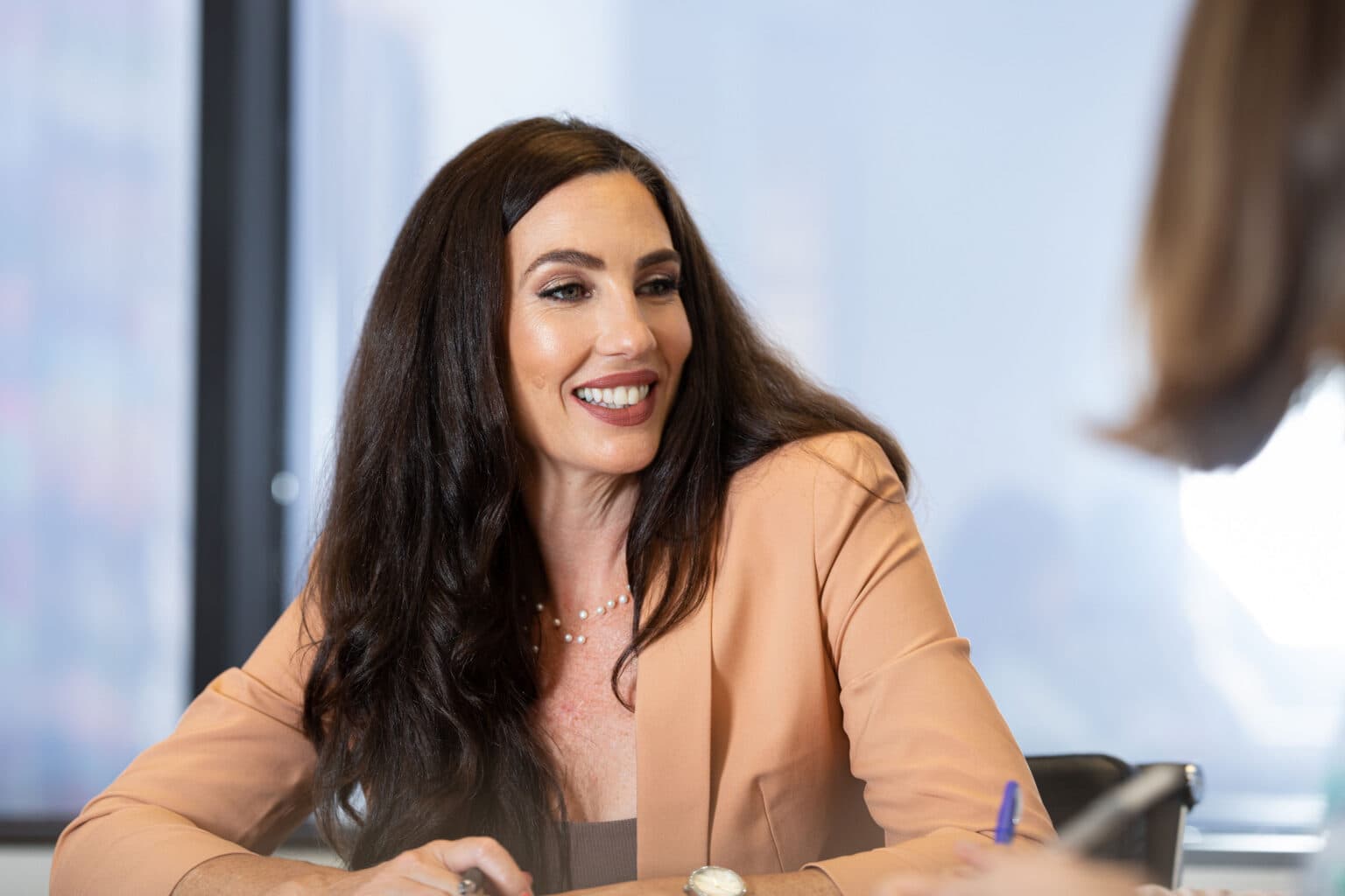 Smiling woman photographed in a modern office for a warm personal branding portrait.