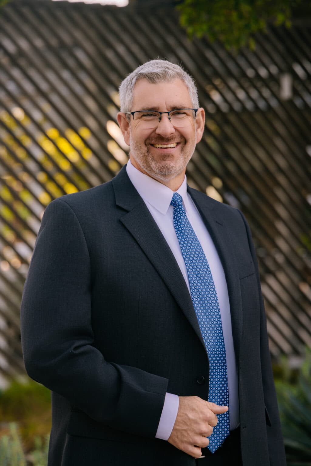 Smiling professional in a suit and tie posing outdoors for corporate headshots in San Diego.
